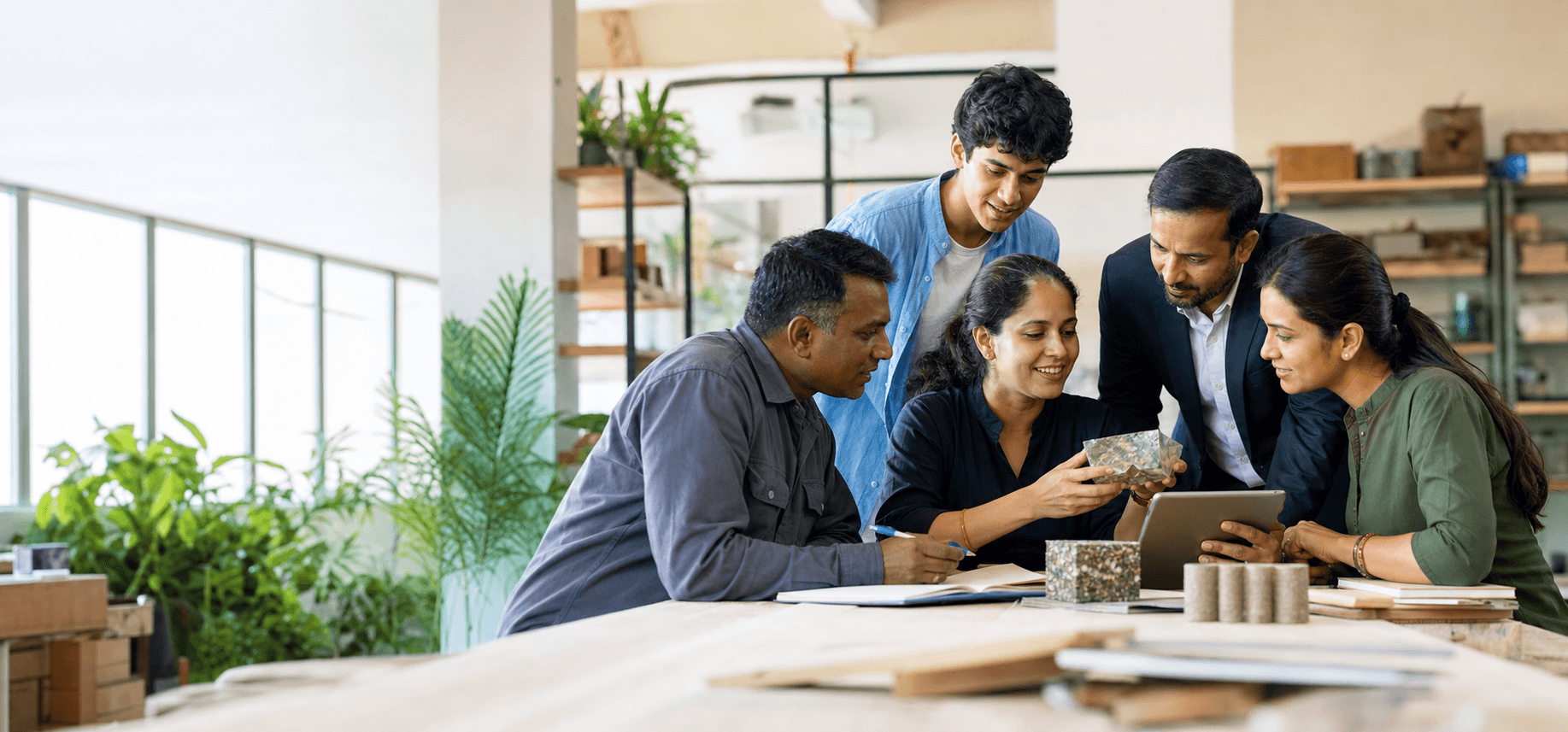 A diverse team of founders, operators, and innovators reviewing sustainable material prototypes in an Indian studio.